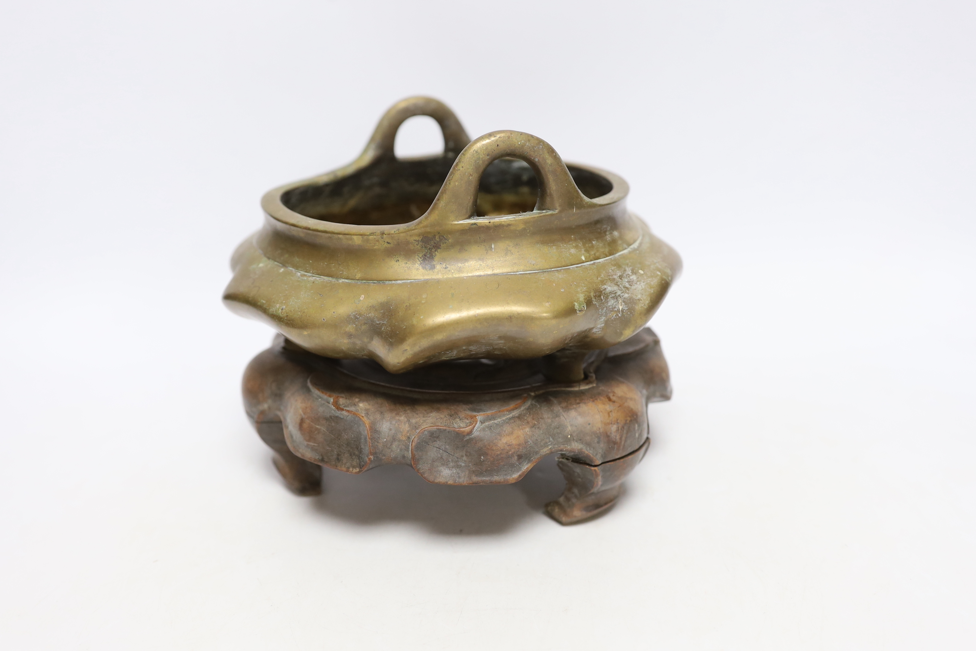 A Chinese bronze tripod censer with twin handles on hardwood stand, censer 19cm wide